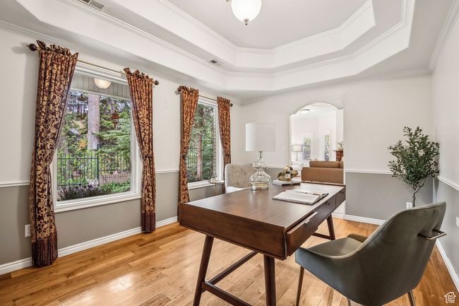 Office space featuring light wood floors, ornamental molding, a tray ceiling, and arched walkways | Image 17