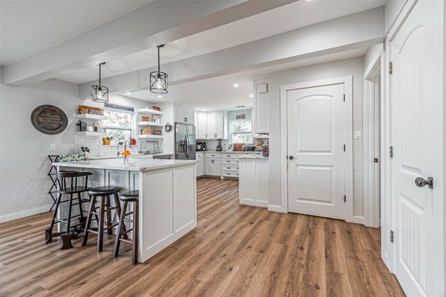 Kitchen with stainless steel fridge, a peninsula, white cabinets, backsplash, and recessed lighting | Image 8