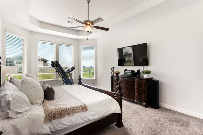 Bedroom with light carpet, baseboards, visible vents, ceiling fan, and a raised ceiling | Image 21