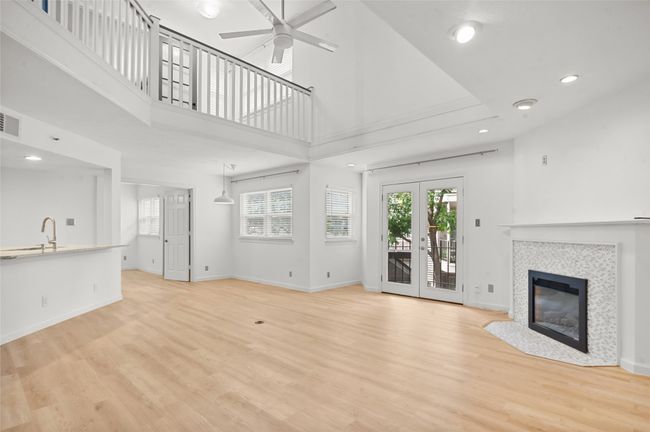 Unfurnished living room featuring a ceiling fan, light wood-type flooring, a fireplace, recessed lighting, and a sink | Image 4