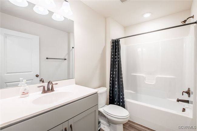 Full bath featuring vanity, shower / tub combo, and wood finished floors | Image 37