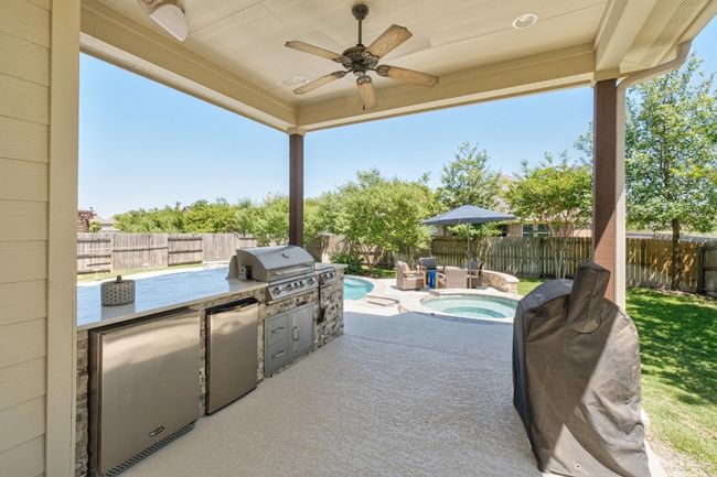 View of patio featuring a ceiling fan, outdoor kitchen and an in ground hot tub | Image 40