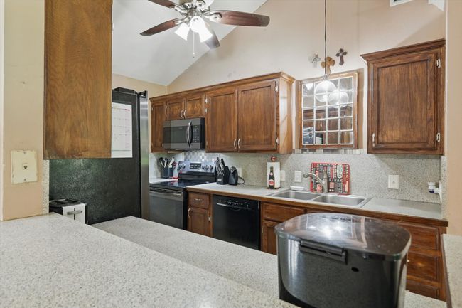 Kitchen with a sink, vaulted ceiling, backsplash, ceiling fan, and appliances with stainless steel finishes | Image 13