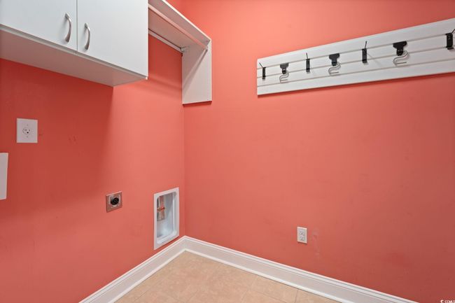 Washroom featuring hookup for an electric dryer, light tile patterned floors, cabinet space, and baseboards | Image 28