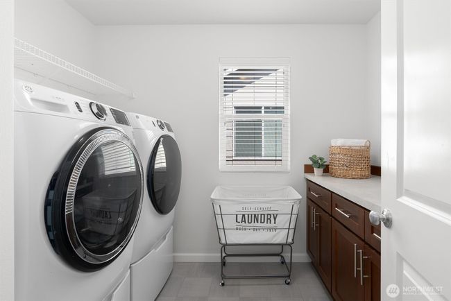 The convenient upstairs laundry room offers built-in storage cabinetry and a folding counter. Full capacity front load washer and dryer with pedestals are included! | Image 25