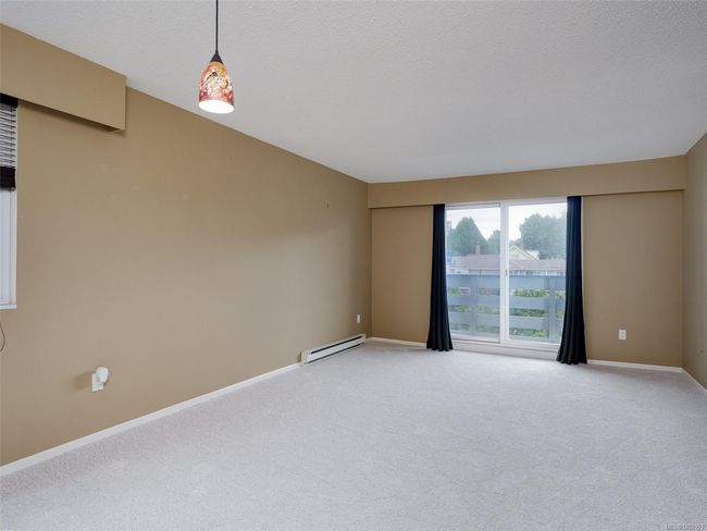 Empty room with a baseboard heating unit, light colored carpet, and a textured ceiling | Image 7