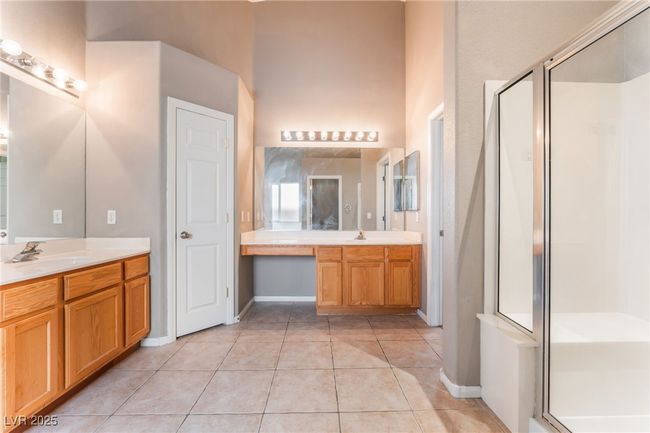 Bathroom featuring tile patterned flooring, a shower stall, a high ceiling, vanity, and baseboards | Image 30