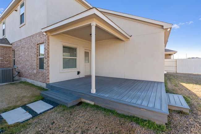Rear view of property with stucco siding, fence, a wooden deck, central air condition unit, and brick siding | Image 35