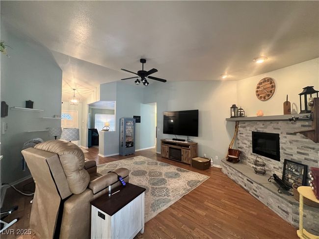 Living area featuring a fireplace, ceiling fan, and wood finished floors | Image 7