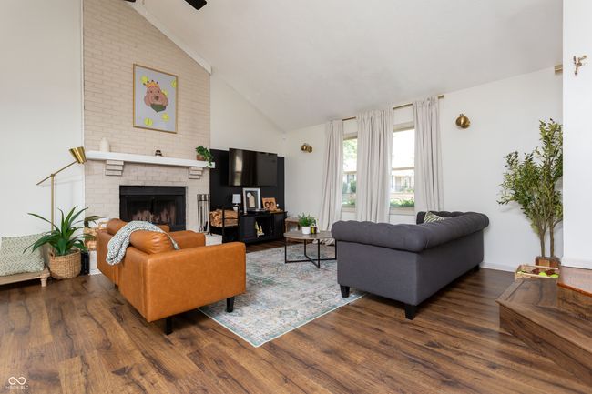 living area featuring a fireplace, wood finished floors, high vaulted ceiling, and a ceiling fan | Image 7