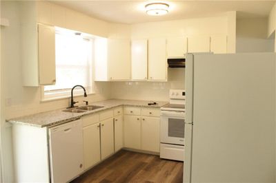 Kitchen featuring white cabinets, white appliances, light stone countertops, sink, and dark hardwood / wood-style floors | Image 2