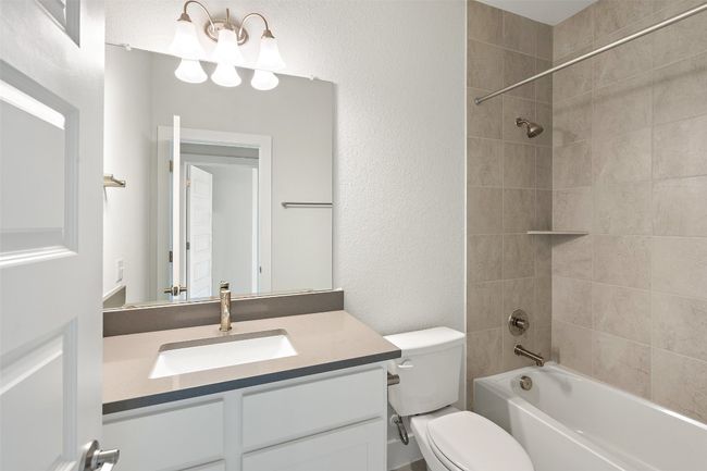 Full bath featuring vanity, shower / bath combination, and a textured wall | Image 35