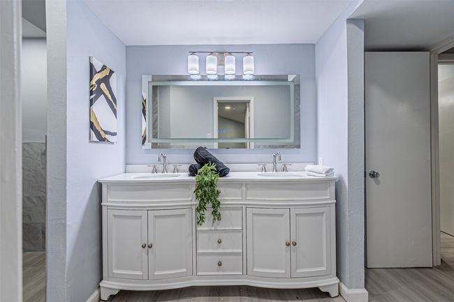Full bath featuring double vanity, a sink, baseboards, and wood finished floors | Image 14