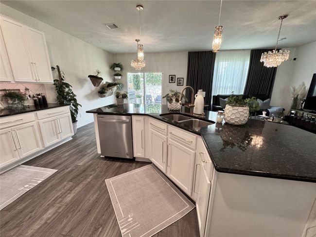 Kitchen featuring dishwasher, a chandelier, dark wood-type flooring, and white cabinets | Image 12