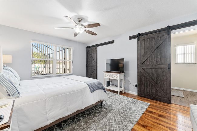 Primary Suite with lighted ceiling fan and barn door access to walk in closet and en suite bath. Furnishings are optional. | Image 14