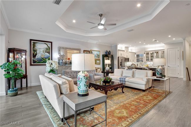 Featuring wide plank tile flooring flooring, a tray ceiling, crown molding, and ceiling fan | Image 8