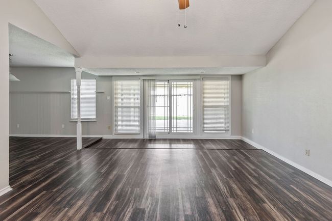 Unfurnished living room with wood finished floors, baseboards, and decorative columns | Image 8