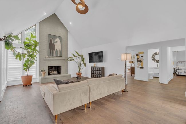 Living room featuring a brick fireplace, baseboards, wood finished floors, and high vaulted ceiling | Image 9