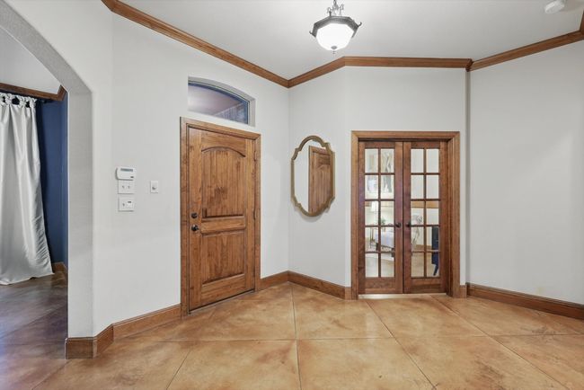 Entrance foyer featuring french doors, ornamental molding, finished concrete flooring, and arched walkways | Image 6