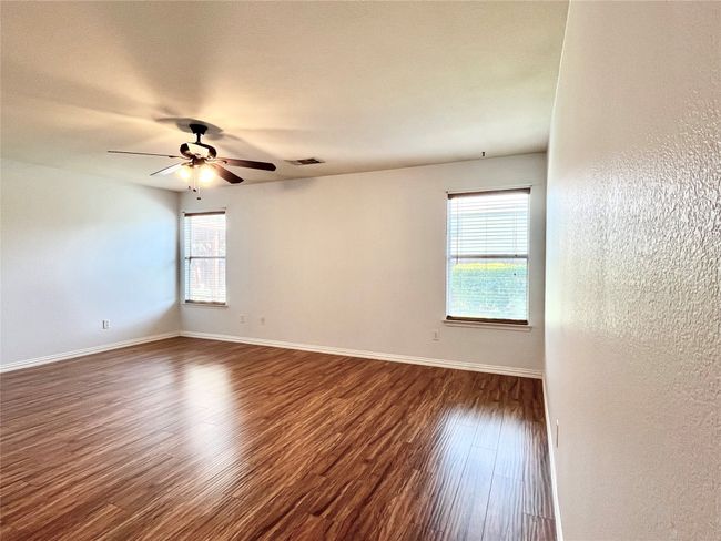 Unfurnished room with healthy amount of natural light, ceiling fan, and dark wood-style floors | Image 28