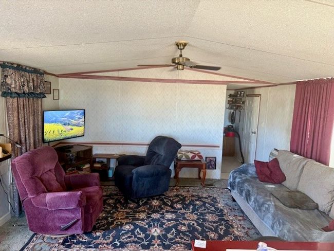 Carpeted living area with lofted ceiling, ceiling fan, and a textured ceiling | Image 18