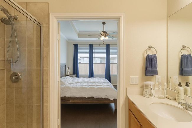 Ensuite bathroom with crown molding, ceiling fan, vanity, and a tile shower | Image 10