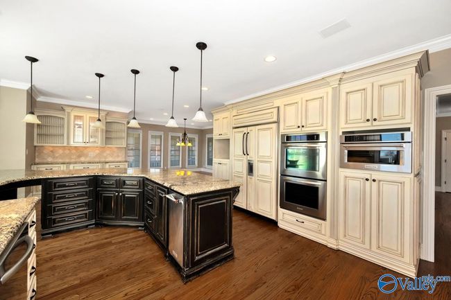 Wood flooring, wood cabinetry, kitchen island with bar seating, recessed lighting | Image 16