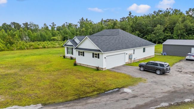 View of home's exterior with a shingled roof, a yard, an attached garage, and driveway | Image 39
