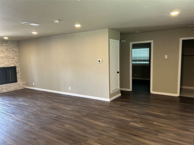 Unfurnished living room with dark wood-style flooring, baseboards, a stone fireplace, and recessed lighting | Image 12