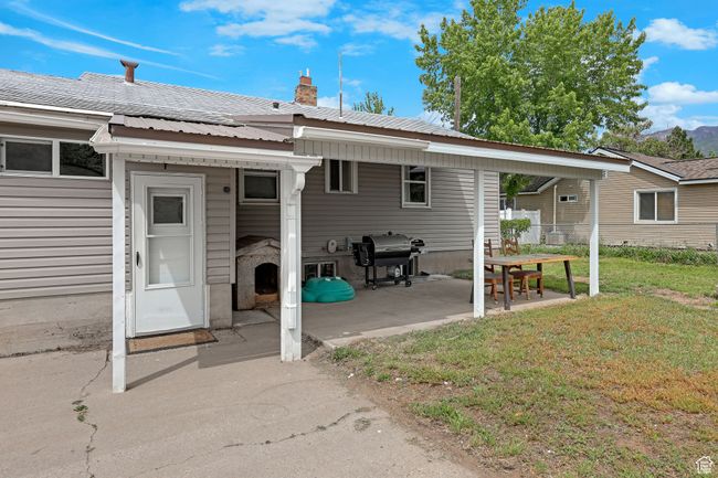 Rear view of house with a lawn, metal roof, a chimney, and a patio | Image 29
