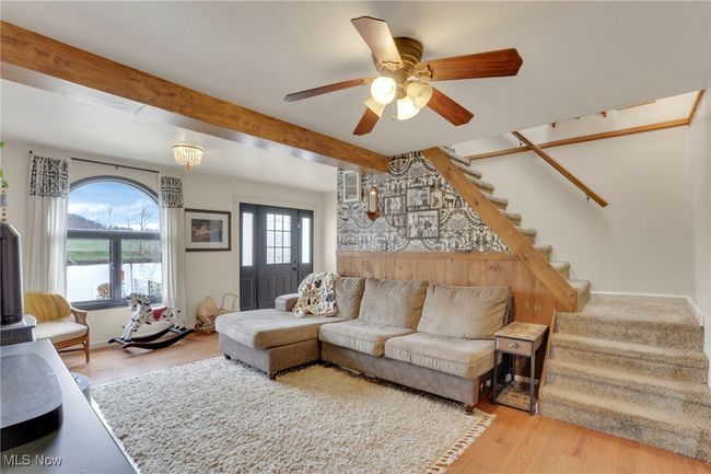 Living area with stairway, beamed ceiling, wood finished floors, and a ceiling fan | Image 9