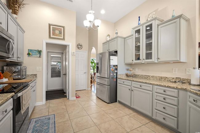 Kitchen featuring appliances with stainless steel finishes, arched walkways, glass insert cabinets, gray cabinets, and a high ceiling | Image 5