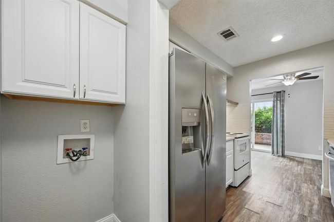 Laundry area featuring cabinet space, a ceiling fan, a textured ceiling, wood finished floors, and washer hookup | Image 17