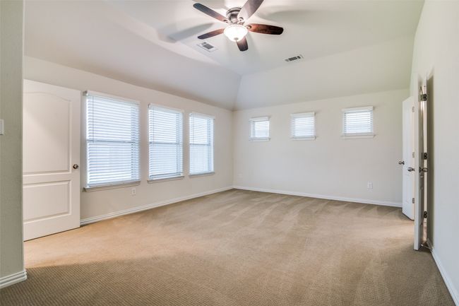 Primary bedroom with light colored carpet, ceiling fan, and vaulted ceiling | Image 13