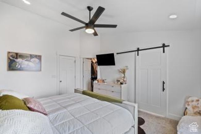 Bedroom with a barn door, a ceiling fan, baseboards, lofted ceiling, and carpet flooring | Image 17