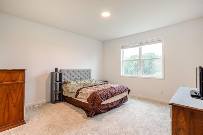 Spacious and serene main-floor primary bedroom with plush carpeting and large window overlooking peaceful greenery. | Image 17