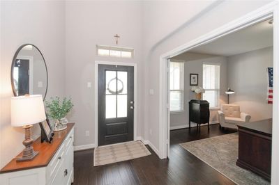 A welcoming entryway with a modern front door leading into a bright space with high ceilings, a neutral color palette, and hardwood floors. | Image 2