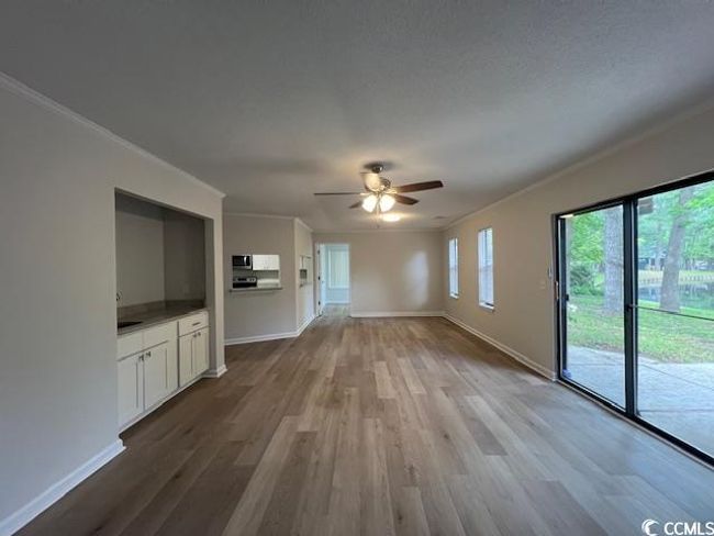 Unfurnished living room featuring crown molding, baseboards, ceiling fan, and wood finished floors | Image 32