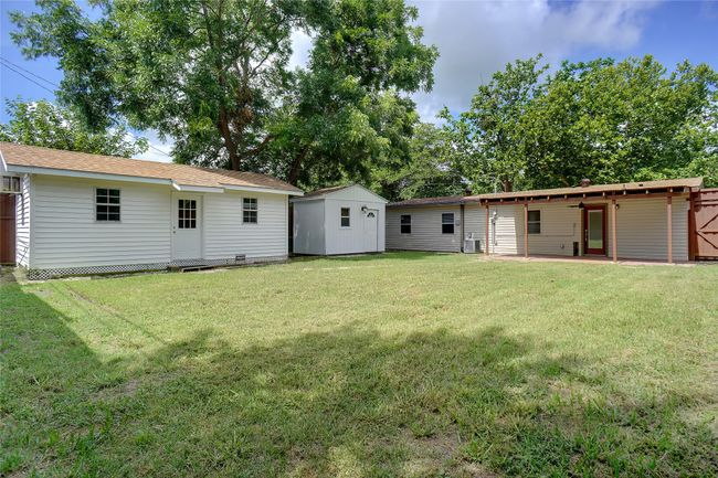 Rear view of property with two outbuilding and a huge lawn with a covered patio | Image 25
