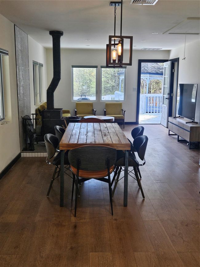 Dining area featuring dark wood-type flooring, a wood stove, and baseboards | Image 9
