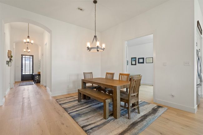 Dining room featuring arched walkways, a chandelier, and light wood-style flooring | Image 17