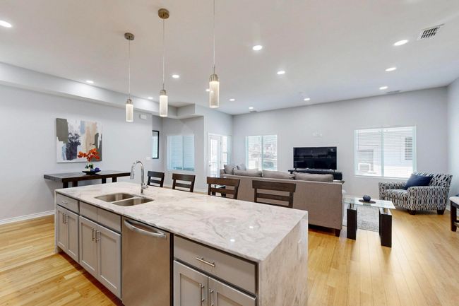 Kitchen featuring a sink, stainless steel dishwasher, gray cabinets, open floor plan, and a kitchen island with sink | Image 4
