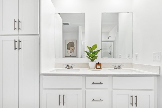 (Photo of model home, features will vary) Featuring a glass-enclosed shower with built-in shelving and glass mirrors set atop dual quartz sinks and vanity-cabinetry, the en-suite bathroom helps streamline morning routines | Image 11