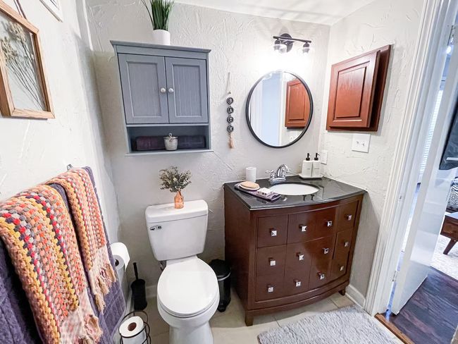 Bathroom with tile patterned flooring, toilet, vanity, and a textured wall | Image 12
