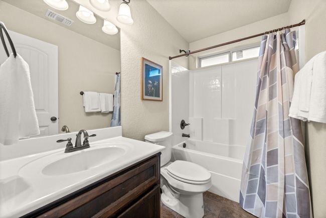 Bathroom featuring shower / bathtub combination with curtain, vanity, and a textured wall | Image 23