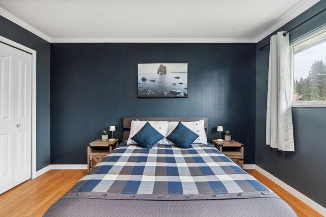 Bedroom featuring crown molding, wood finished floors, an accent wall, and baseboards | Image 21