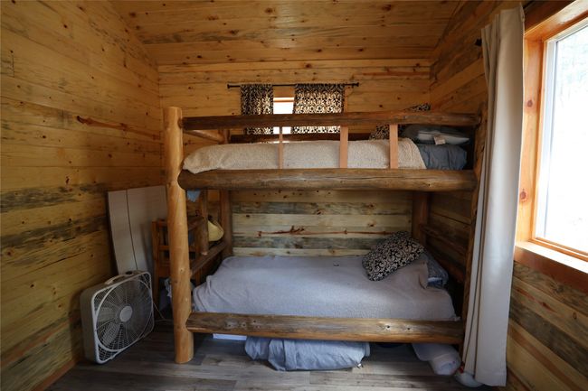 Unfurnished bedroom with multiple windows, vaulted ceiling, wooden walls, wood ceiling, and wood finished floors | Image 43