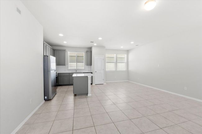 Kitchen with gray cabinets, light countertops, a center island, freestanding refrigerator, and backsplash | Image 7