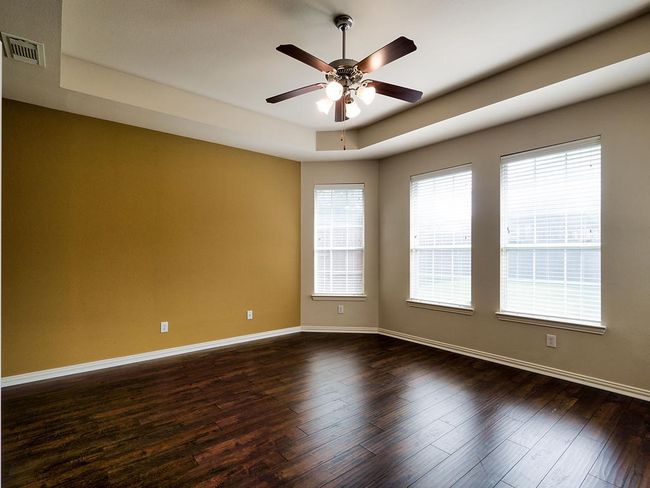 Empty room featuring a raised ceiling, ceiling fan, baseboards, and dark wood finished floors | Image 27