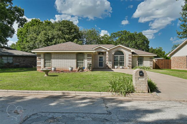 Ranch-style house featuring brick siding, a shingled roof, and concrete driveway | Image 40